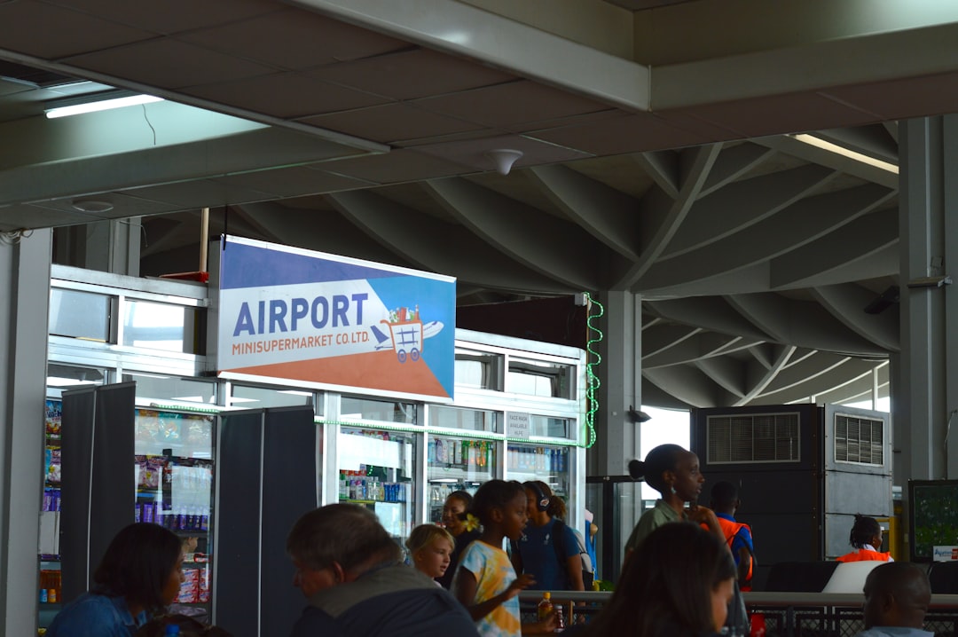 Pessoas Em Um Terminal De Aeroporto Perto De Uma Placa ynA_xWeLv78